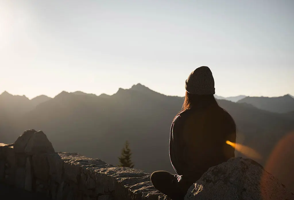 personne qui fait de la sophrologie face à une montagne